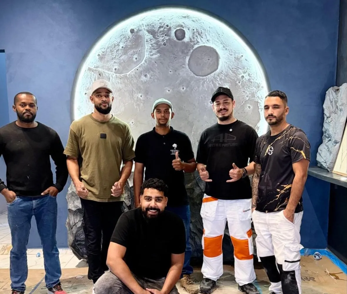 Paulinho com alunos da turma do curso presencial, diante do painel de Lua em relevo iluminado